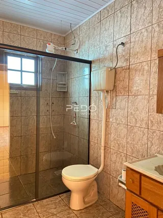 Foto de um banheiro com box de vidro e vaso sanitário em um imóvel.