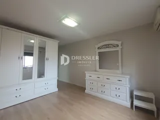 Quarto com armários brancos e piso de madeira clara.