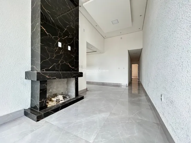 Ambiente interno com lareira de mármore e piso claro em um espaço amplo.