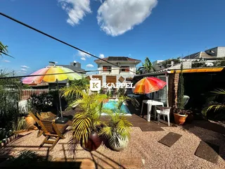 Área externa com piscina e móveis de jardim em um dia ensolarado.