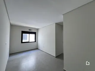Vista interna de um ambiente com paredes brancas e piso cinza claro.