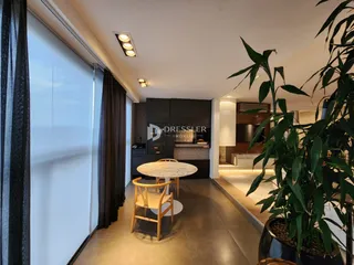 Interior de uma sala de jantar com mesa redonda e janelas amplas.