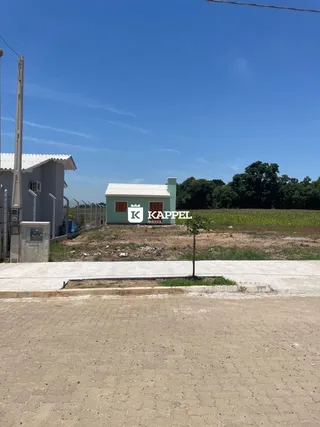 Foto da fachada de uma casa simples em uma área com campo aberto.