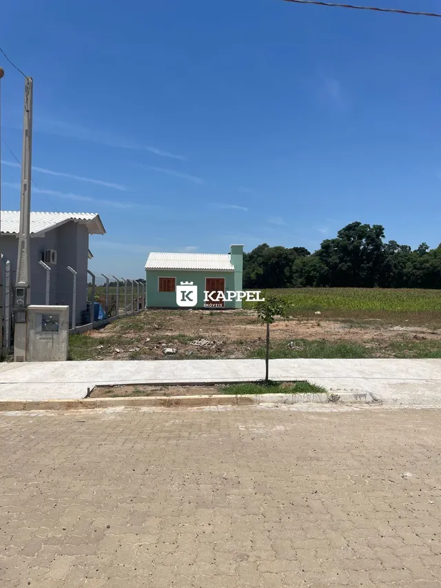 Foto da fachada de uma casa simples em uma área com campo aberto.