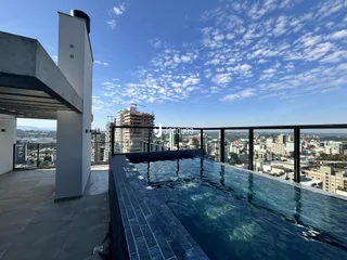 Vista panorâmica de um terraço com piscina e vista da cidade.