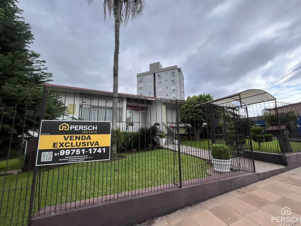 Foto da fachada de um imóvel residencial em Lajeado, Brasil, com cerca e vegetação.
