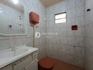 Foto de um banheiro com revestimento de azulejos brancos e piso de cerâmica marrom.