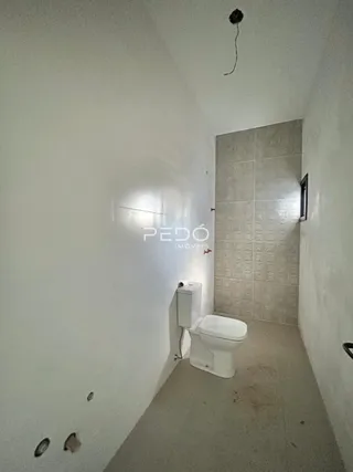 Foto de um corredor com banheiro revestido de azulejos brancos.