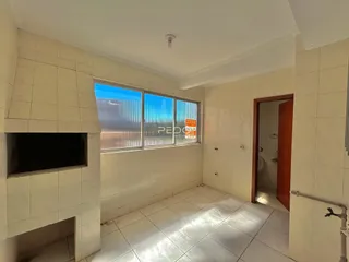 Interior de uma área comum com piso de cerâmica clara e janela.
