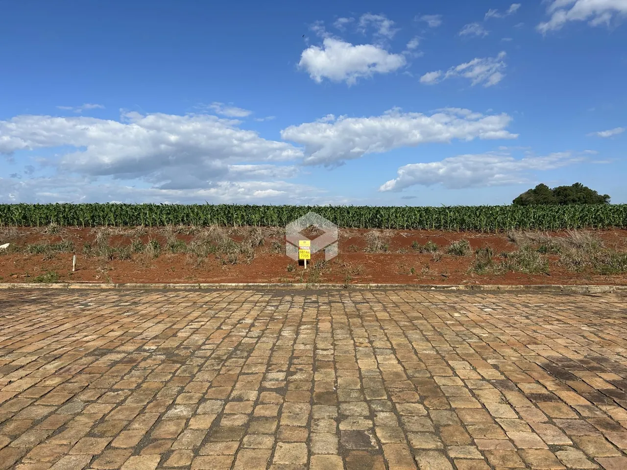 Vista de uma propriedade com um campo de cultivo ao fundo.