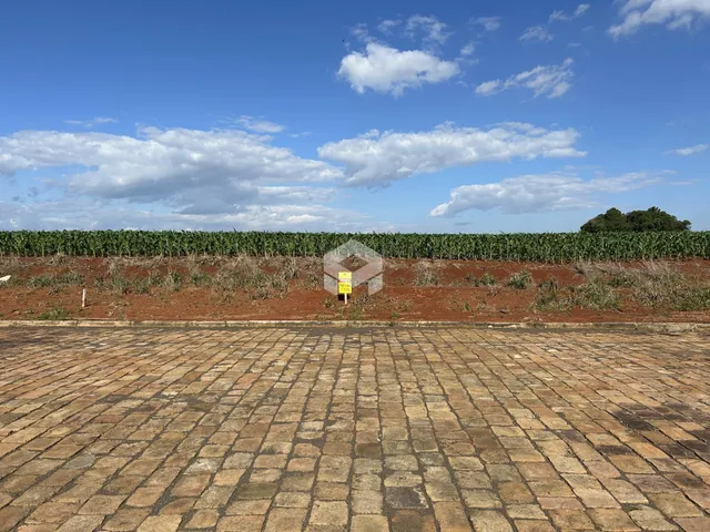 Vista de uma propriedade com um campo de cultivo ao fundo.