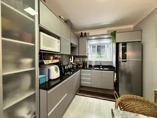 Vista interna de uma cozinha moderna com armários e eletrodomésticos.
