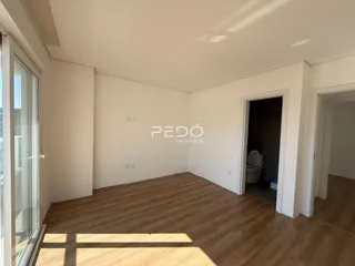 Sala de estar com piso de madeira e grande janela.