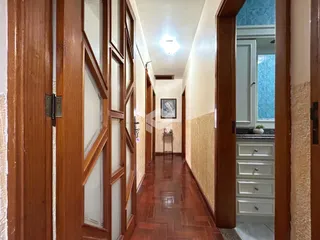 Corredor interno de uma residência com piso de cerâmica e portas de madeira.