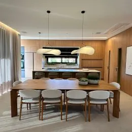 Mesa de jantar de madeira com cadeiras em um ambiente interno.