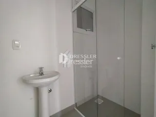 Vista parcial de um banheiro interno com louças brancas.