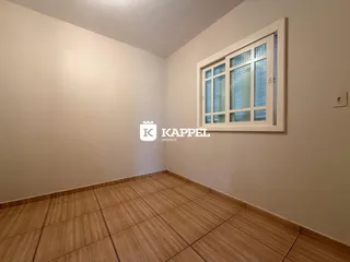 Vista de um cômodo interno com piso de madeira e uma janela na parede.