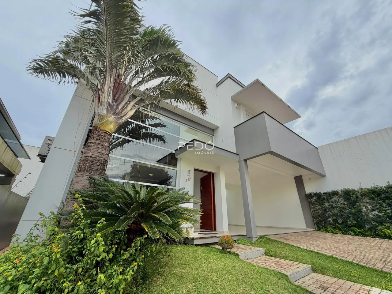 Fachada moderna de uma residência em Lajeado, Brasil, com paisagismo tropical.
