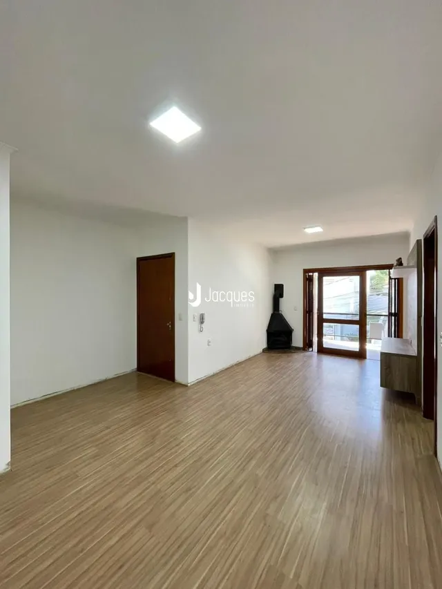 Ambiente interno de uma sala ampla com piso de madeira clara.