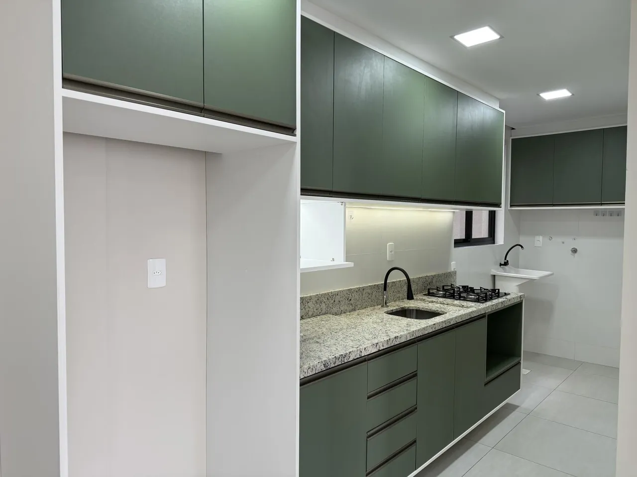 Foto de uma cozinha moderna com armários verdes e bancada de granito.