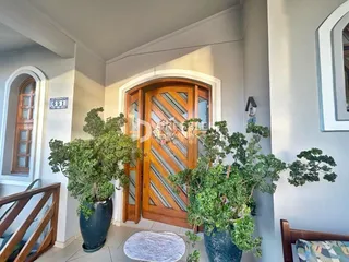 Entrada da residência com porta de madeira e plantas decorativas.