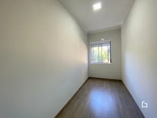 Vista de um corredor interno com piso de madeira clara.