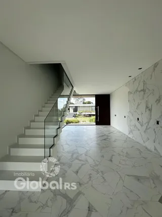 Hall de entrada com escadaria de vidro e piso em mármore claro.