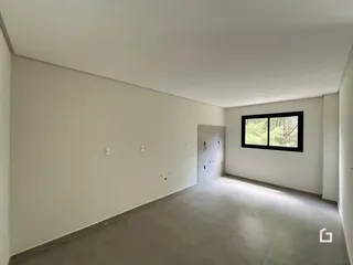 Vista interna de um ambiente com paredes brancas e piso cinza claro.
