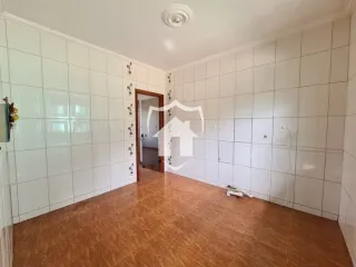 Interior de um ambiente com paredes brancas e piso de cerâmica marrom.