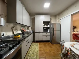 Foto de uma cozinha com armários brancos e piso de cerâmica.