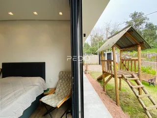Quarto com vista para o quintal e estrutura de madeira no exterior.