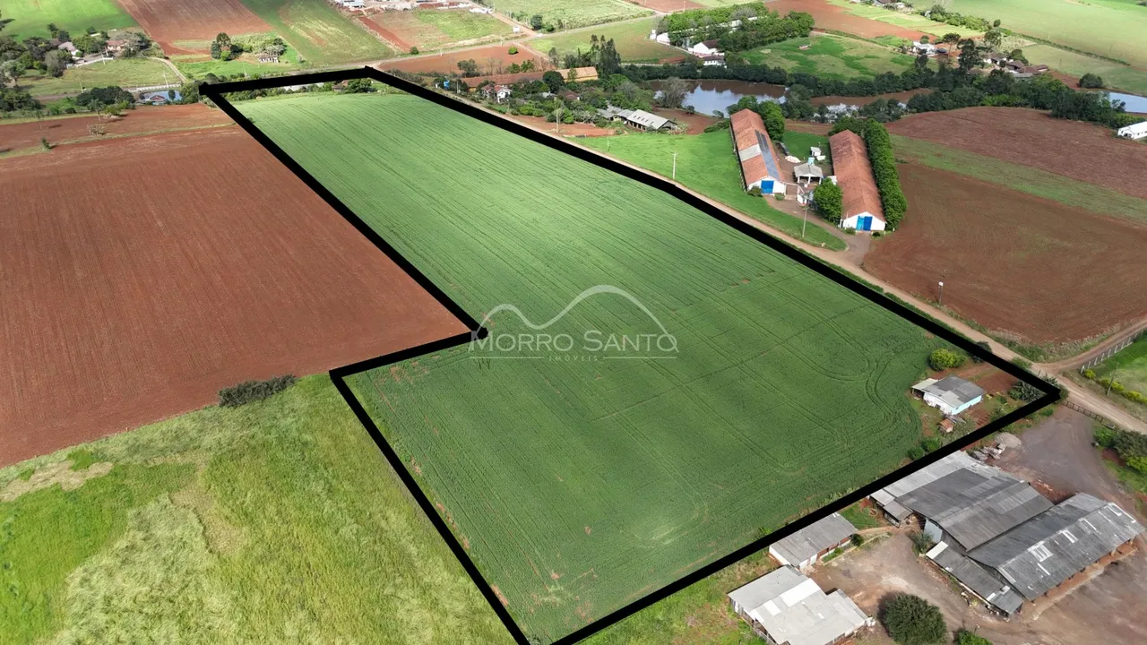Vista aérea de uma propriedade rural com campos cultivados e estruturas rurais.