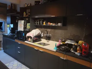 Uma cozinha moderna com armários escuros e bancada clara.