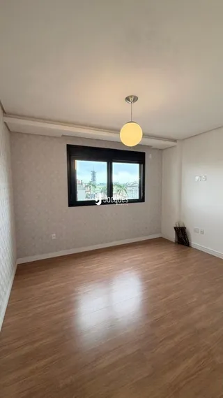 A sala apresenta piso de madeira e uma grande janela.