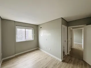 Uma sala de estar com piso de madeira clara e paredes cinzas.