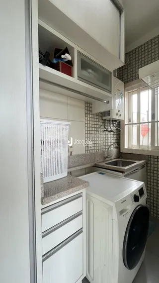 Vista interna de uma cozinha com armários brancos e revestimento de azulejos.