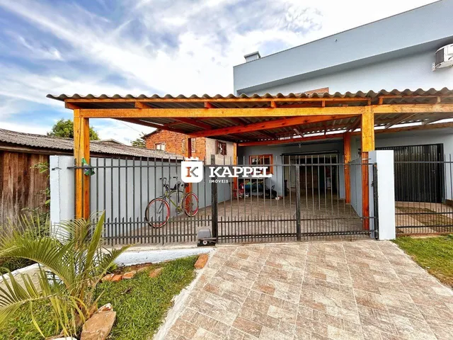 Vista externa de uma casa com estrutura de cobertura de madeira e portão de metal.