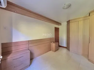 Quarto com armários em madeira e piso de cerâmica.