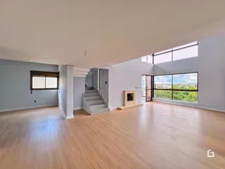 Sala de estar ampla com piso de madeira clara e grande janela.