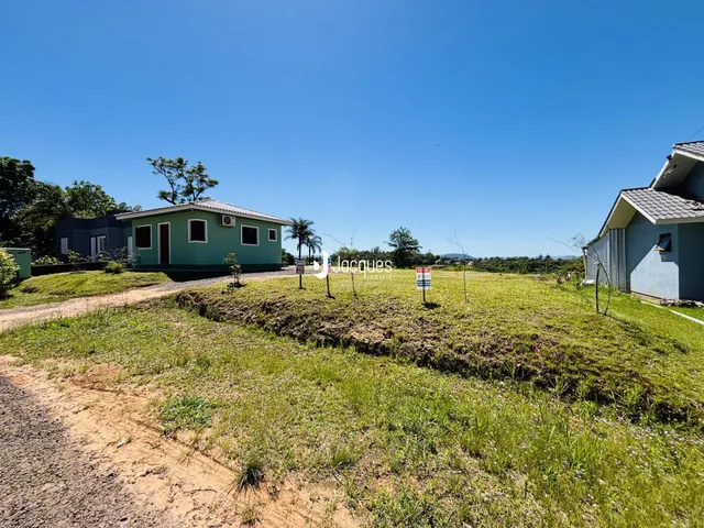 Vista externa de duas casas em Lajeado, Brasil, com terreno gramado em primeiro plano.