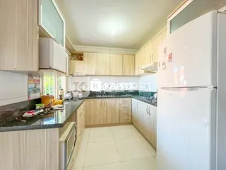 Esta é uma foto de uma cozinha com armários brancos e bancadas escuras.