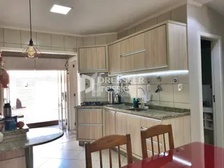 Vista da cozinha com armários de madeira clara e bancadas.