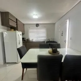 Sala de estar com mesa branca e janelas cobertas por persianas.