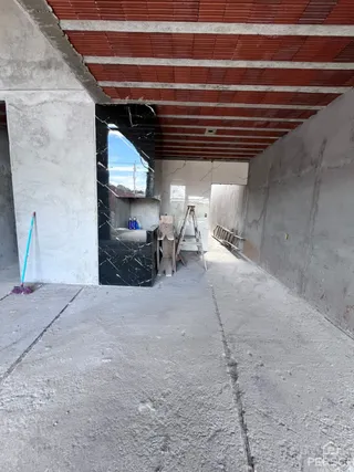Foto de um espaço interno em fase de reforma com paredes de concreto aparente.