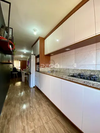 Vista interna de uma cozinha com armários brancos e bancada de granito.