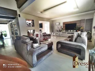 Uma sala de estar interna com dois sofás cinzas e uma televisão.