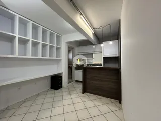 Interior de uma sala de estar com estantes brancas e piso de cerâmica clara.