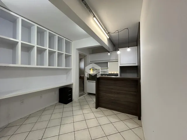 Interior de uma sala de estar com estantes brancas e piso de cerâmica clara.