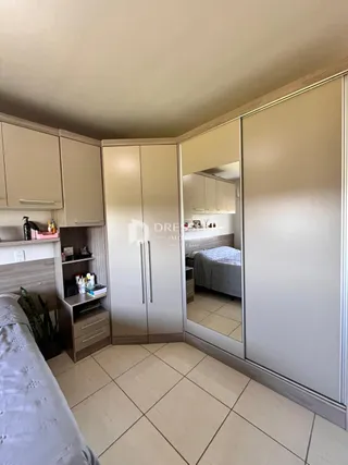 Quarto com armários em madeira clara e piso de cerâmica