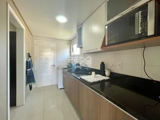 Vista da cozinha com armários e bancada escura em um imóvel brasileiro.
